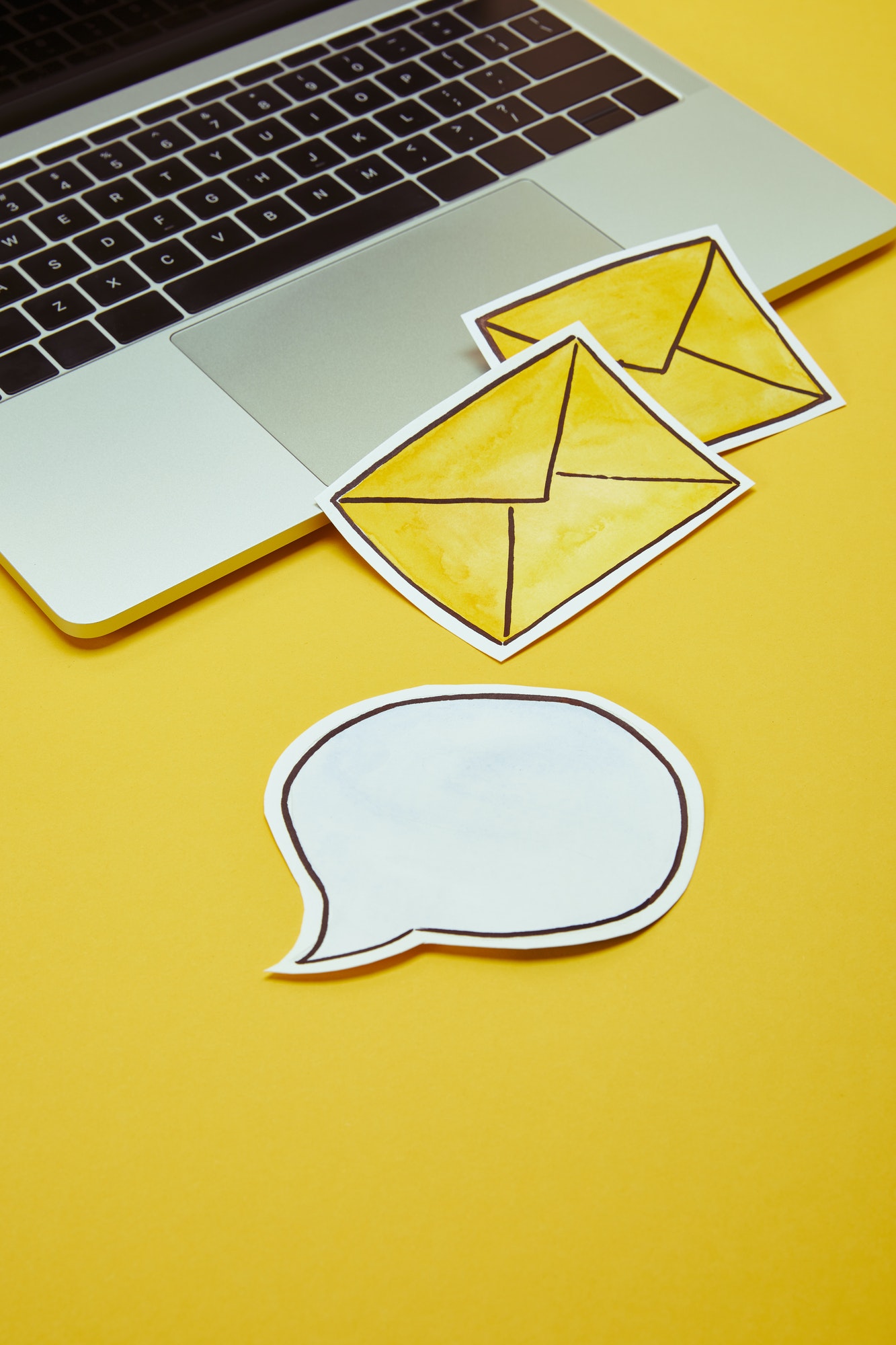 message signs, speech bubble and laptop on yellow surface